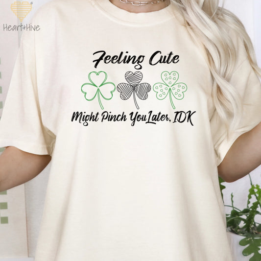 Ivory Comfort Color tee with three delicate shamrock outlines saying 'Feeling cute might pinch you later, idk'.