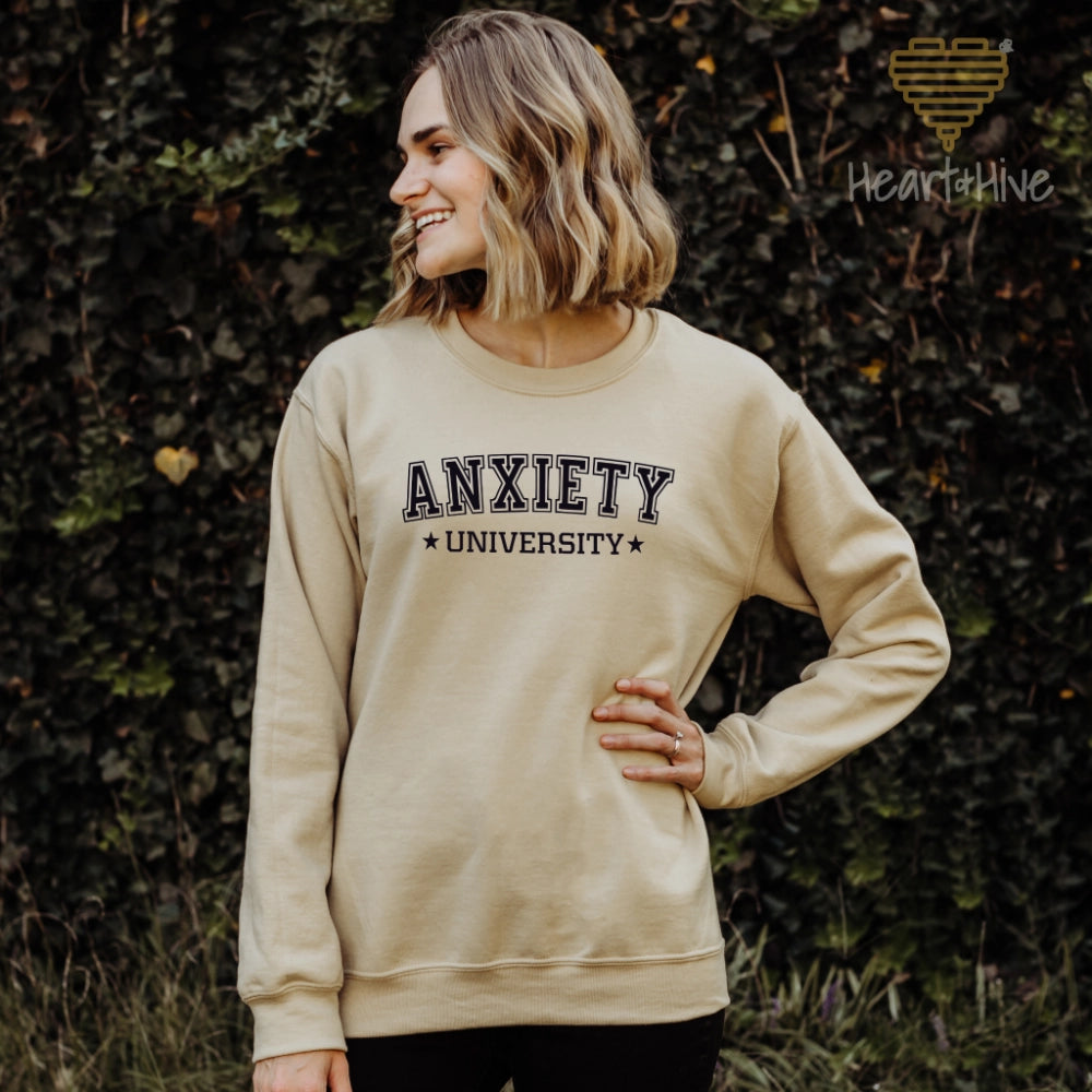 Sand crewneck sweatshirt with 'Anxiety University' in bold, white collegiate font, framed by small stars.