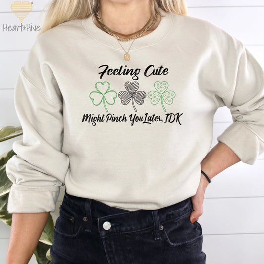 Sand sweatshirt with three delicate shamrock outlines saying 'Feeling cute might pinch you later, idk'.