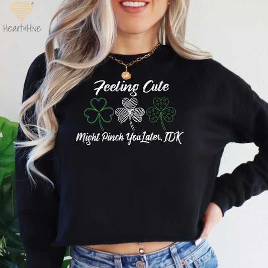 Black crop crewneck fleece with three delicate shamrock outlines saying 'Feeling cute might pinch you later, idk'.