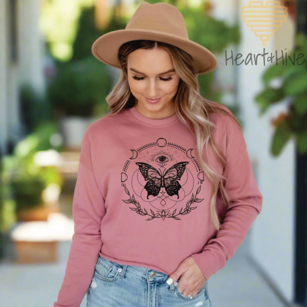Mauve cropped sweatshirt fleece with a black design of a butterfly, all-seeing eye, crescent moons, celestial symbols, and botanicals.