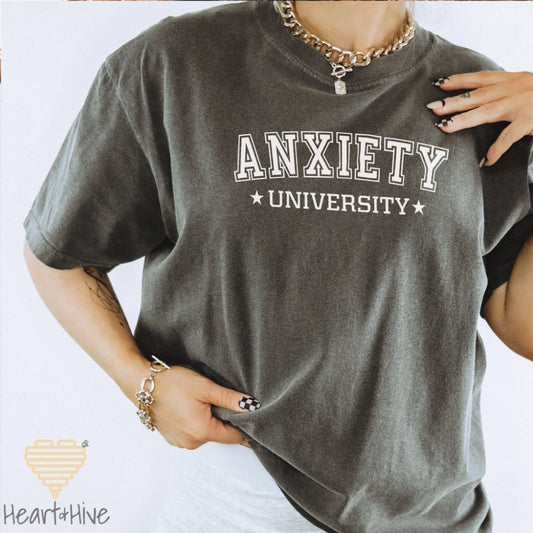 Pepper Comfort Color tee with 'Anxiety University' in bold, white collegiate font, framed by small stars.