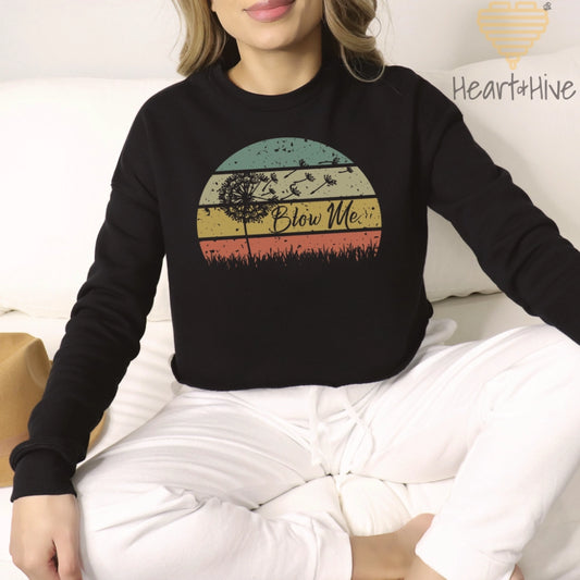 Black cropped fleece with a retro sunset circle, grass, and the faded silhouette of a dandelion and 'Blow Me' text.