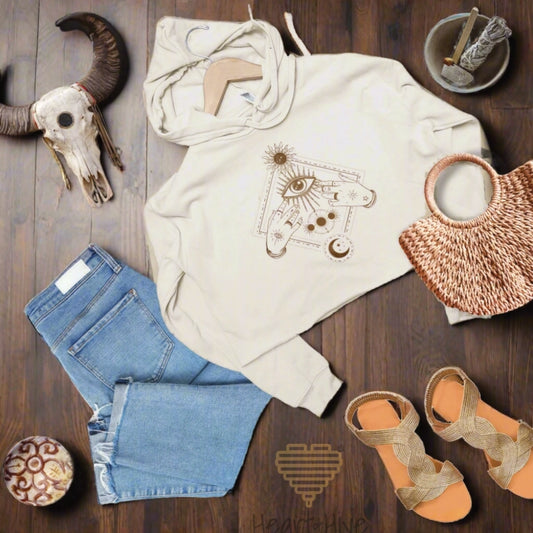 Heather dust cropped hoodie with a bronze mystical design featuring an all-seeing eye, celestial symbols, and hands adorned with stars and moons.