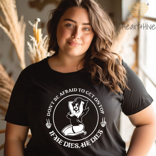 Black tee with a circular design featuring a pin-up style woman, two skull hand peace signs, and the phrase 'Don't be afraid to get on top, if he dies, he dies.