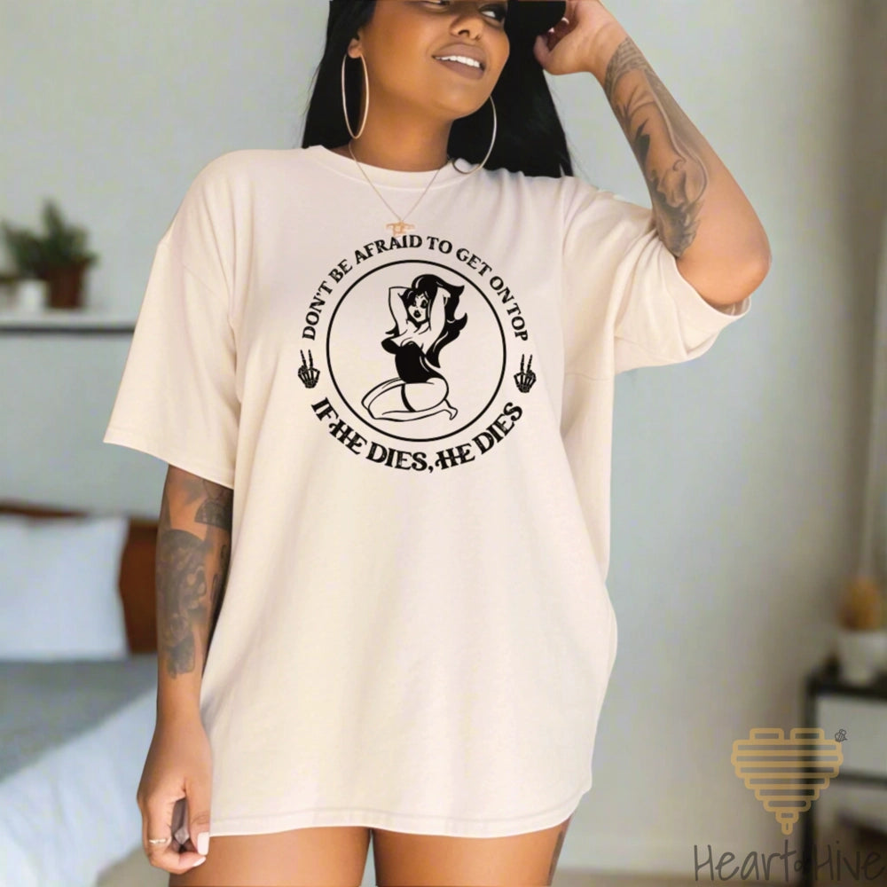 Ivory Comfort Color tee with a circular design featuring a pin-up style woman, two skull hand peace signs, and the phrase 'Don't be afraid to get on top, if he dies, he dies.