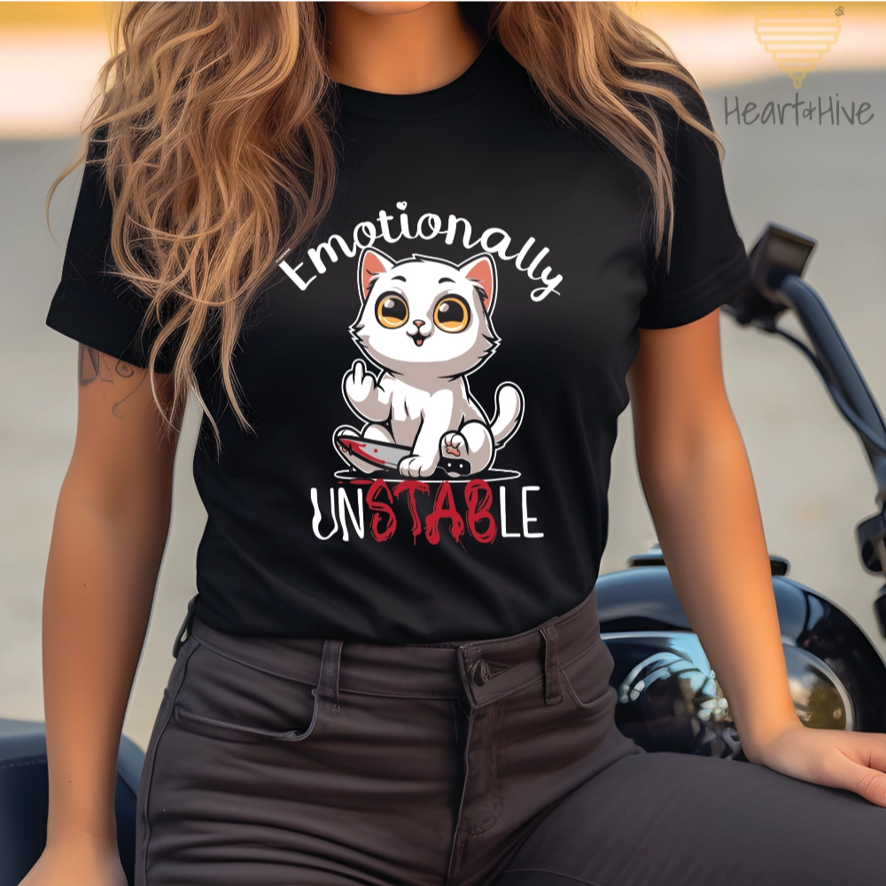 Black tee with a white cat holding a bloody knife with his middle finger up. 'Emotionally' is rounded above and unstable is written below with 'stab' red and dripping.