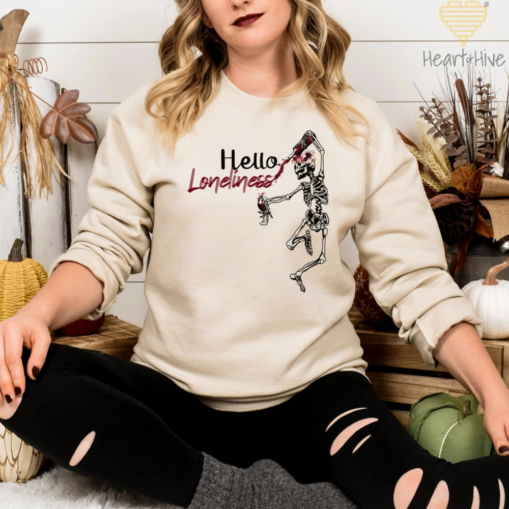 Sand Sweatshirt with a leaping skeleton holding a bottle of wine, splattering red liquid across 'Hello Loneliness' in bold and script fonts.