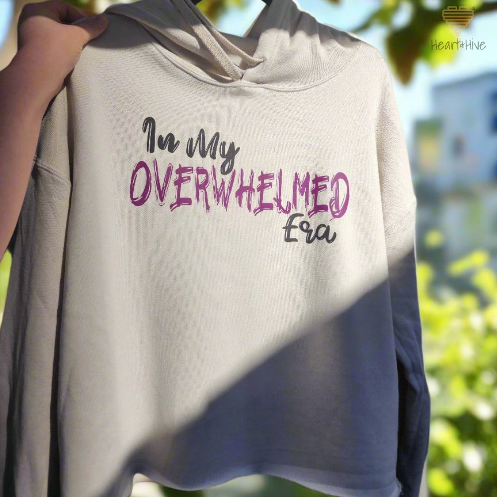 Heather Dust (Beige) crop hoodie with the phrase "In My OVERWHELMED Era," with "OVERWHELMED" in purple font and the rest in black.
