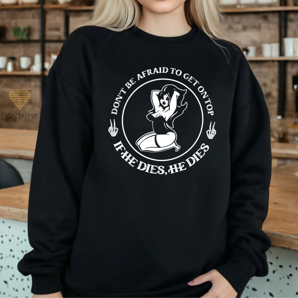 Black sweatshirt with a circular design featuring a pin-up style woman, two skull hand peace signs, and the phrase 'Don't be afraid to get on top, if he dies, he dies.
