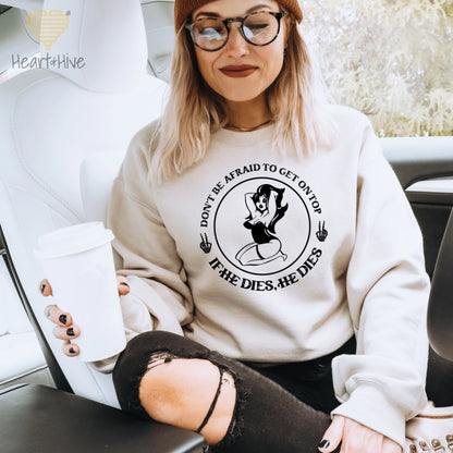 Sand sweatshirt with a circular design featuring a pin-up style woman, two skull hand peace signs, and the phrase 'Don't be afraid to get on top, if he dies, he dies.