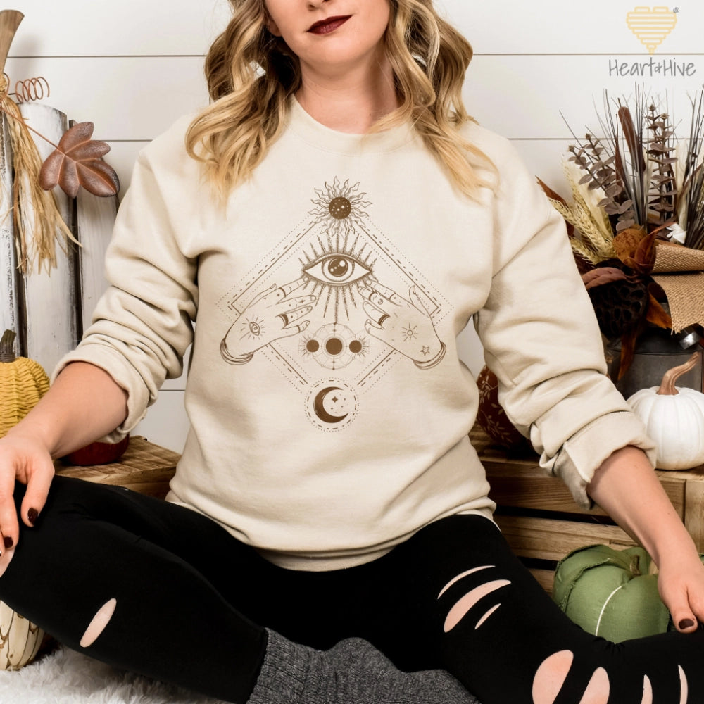 Sand sweatshirt with a bronze mystical design featuring an all-seeing eye, celestial symbols, and hands adorned with stars and moons.