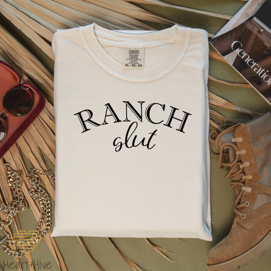 Ivory Comfort color tee with, 'Ranch Slut' with Ranch written in a Western font and slut written in a cute cursive text. 